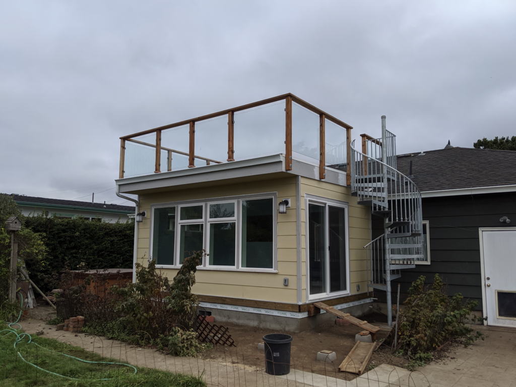 A unique addition with a room with large windows on the first story with a winding staircase going to a deck built on the roof of the addition.