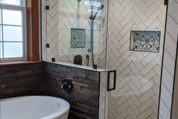 bathroom-remodel A beautiful remodeled bathroom in the Victorian house with white subway tile in the shower, glass doors, a deep bath, black and white tile details, and black hardware throughout.