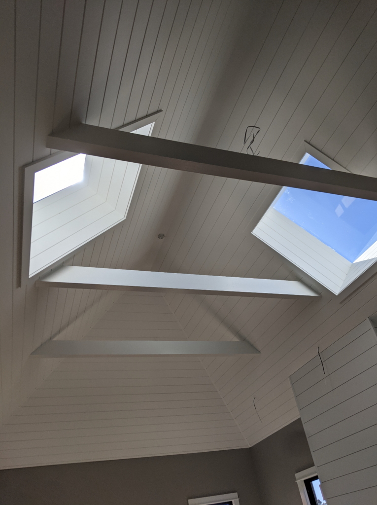 A view of the skylights, beams, and beautiful woodwork on the ceiling of the Shotgun house remodel.
