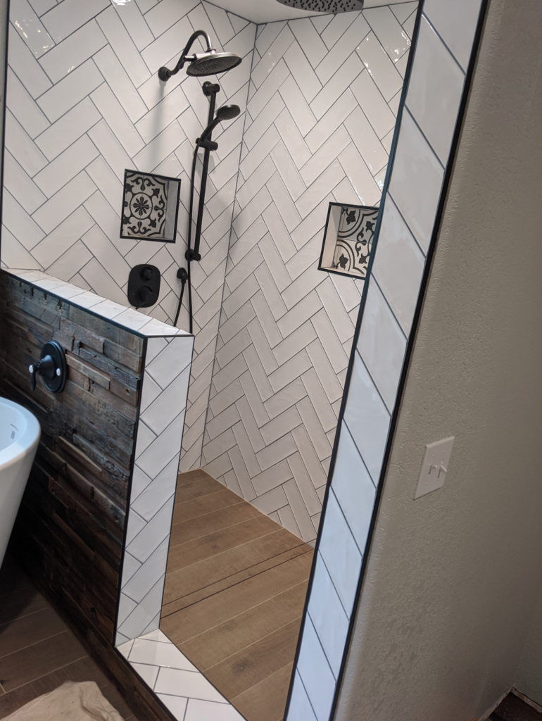 A detailed view of the subway tile and decorative black and white tile, plus the high end black hardware in the remodeled Victorian bathroom.